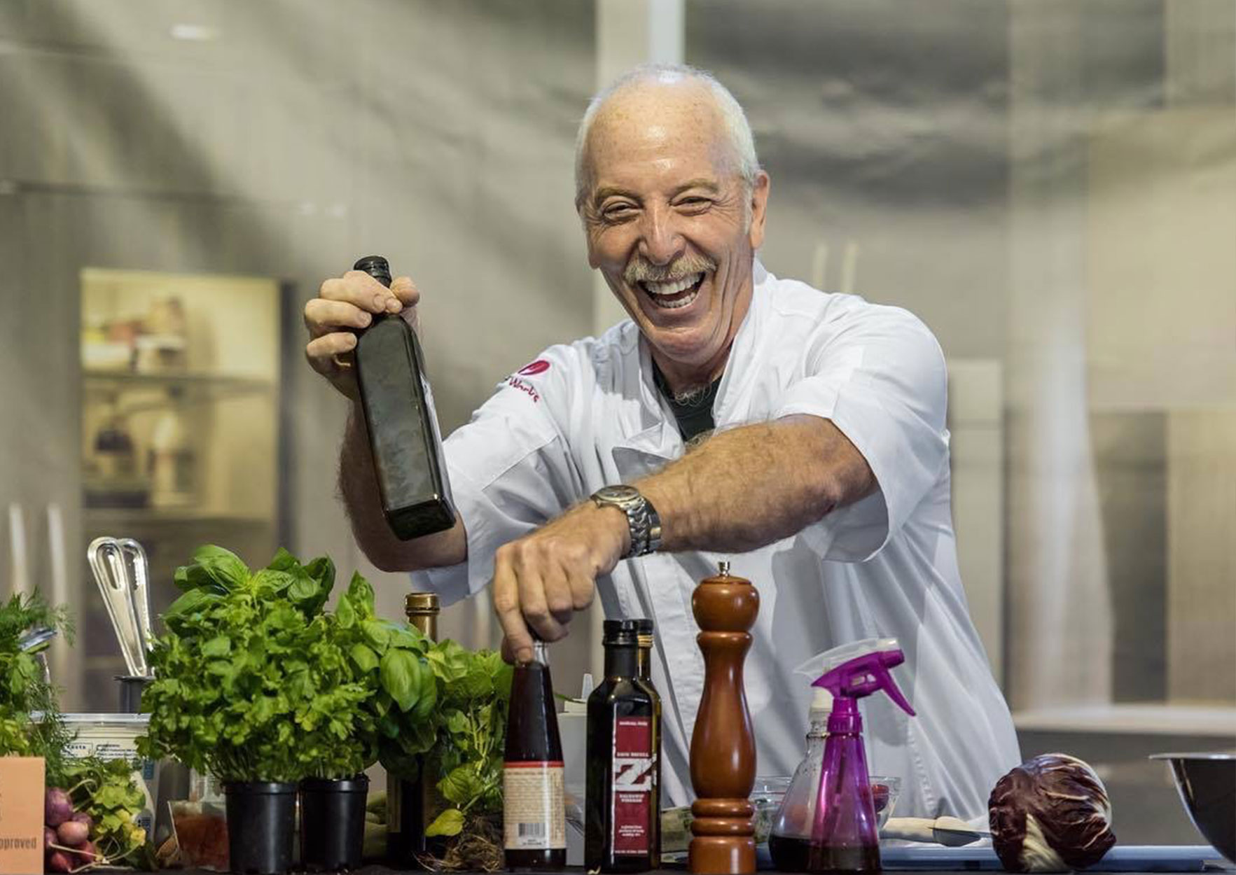 Zack Bruell posing for glamour photographs with olive oil in his kitchen.