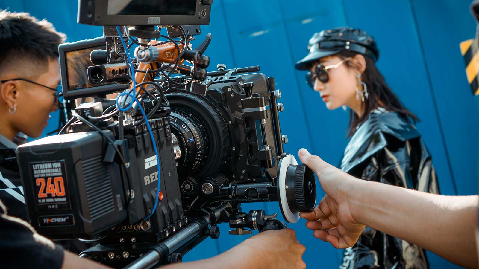 A model being filmed by a videographer holding a large camera.
