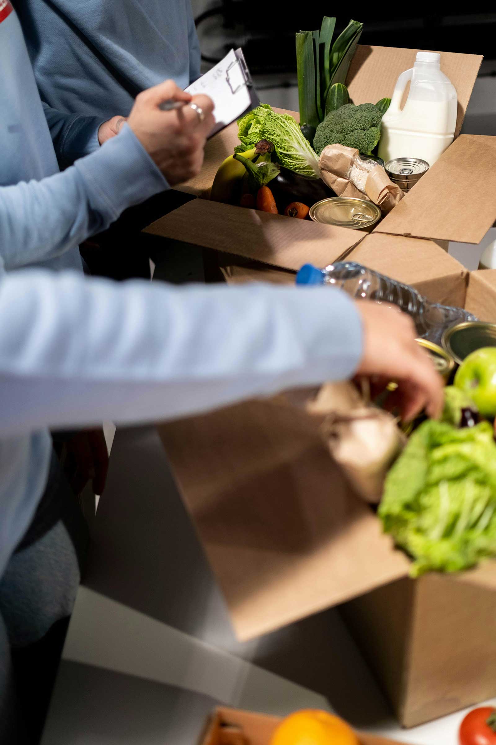 Nonprofit workers fill a box with food for needy communities.